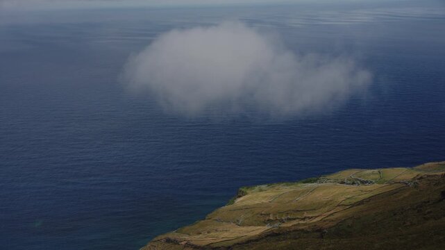 Cinematic Minimalist View of a Single Cloud Over the Deep Blue Atlantic Ocean and Rugged Coastal Cliffs, Corvo Island, Azores