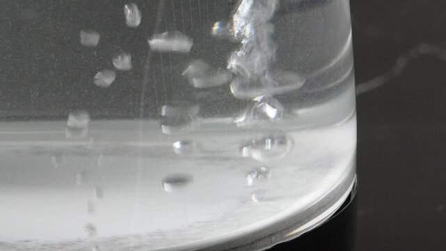 4K water bubbles starting to form and rise inside transparent glass electric kettle, process and hot water preparation.