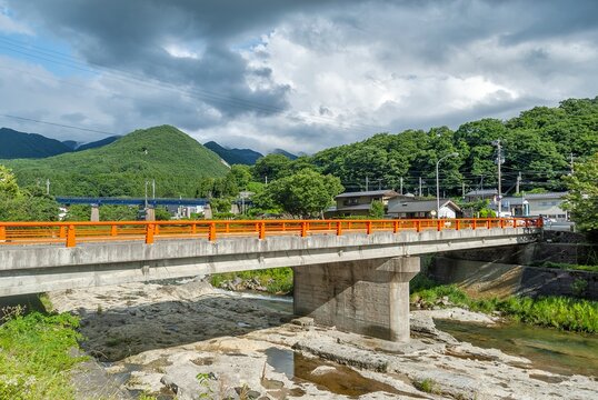 山形市 山寺の玄関口に架かる朱色の宝珠橋と、背景に広がる夏の山並みの風景/Vermilion Hoshubashi Bridge at the Entrance to Risshakuji with Summer Mountains in Yamadera