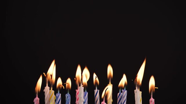 Many colorful birthday candles over black background. Birthday candles with copy space for birthday celebrations, greeting cards, banners, or party decorations design.