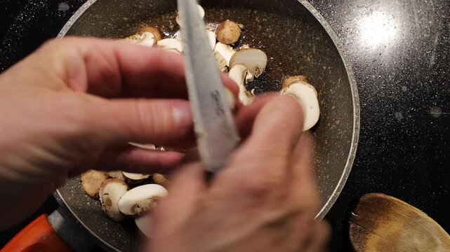 Stockholm, Sweden A cook on a home induction stove cuts and fries mushrooms.
