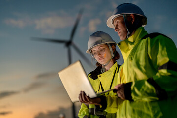Engineers analyzing smart grid data via laptop at onshore wind farm. Integrating AI technology to drive the global clean energy transition. © ultramansk
