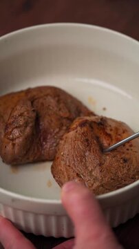 Inserting oven thermometer into lamb roast in ceramic dish