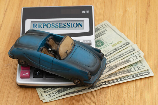 Repossession message with car and calculator on money on wood desk