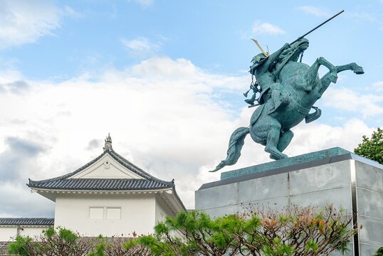 山形市 山形城跡（霞城公園）に鎮座する最上義光公の勇壮な騎馬像と、背後にそびえる白壁の東大手門の櫓門/The Heroic Statue of Yoshiaki Mogami Standing Proudly Beside the White Walls of Higashi-Ote Gate at Yamagata Castle Ruins