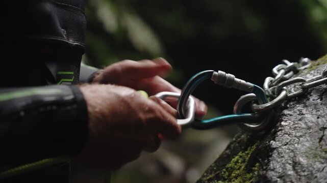Cinematic Close-up of a Person Securing a Locking Carabiner to a Chain Anchor, Canyoning or Rock Climbing Safety Setup