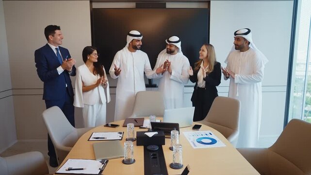 Corporate business event with emirati and western business people international business team collaborating around a conference table reviewing strategy documents and laptops