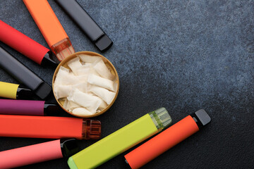 Focus on snus pouches and electronic cigarettes on a dark surface during the day © ir1ska
