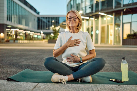 Portrait of a mature middle aged woman stratching and practicing yoga outdoors