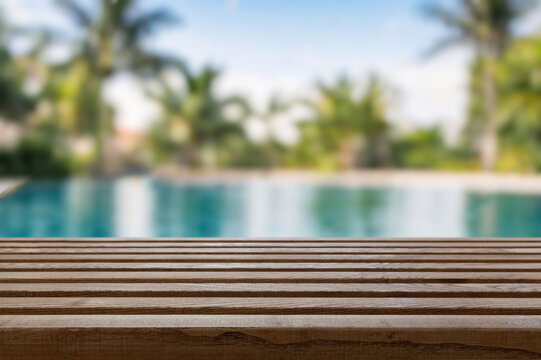 Wooden surface with tropical pool or beach in the background at day