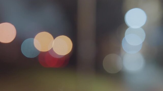 Blurred bokeh night lights soft city glow distant traffic and lampposts rendered as colorful circular highlights hazy atmosphere shallow depth cinematic mood ambient shimmer ideal for background