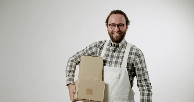 A cheerful man in a white apron and plaid shirt holds cardboard boxes, suggesting a small business owner, delivery service, or e-commerce concept. various retail, shipping, or entrepreneurial themes.