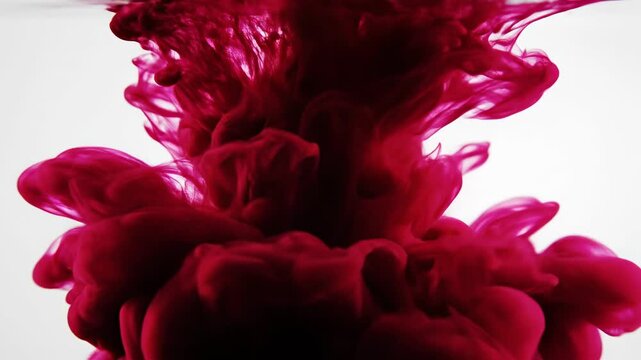 Deep crimson liquid pigments swirling and dissolving in clear water, creating abstract organic shapes and wispy tendrils that beautifully expand outwards, evoking intense emotional depth
