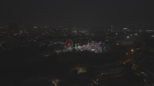LUna park a Karachi in pakistan di notte con ruota panoramica, giochi e luci in movimento ripreso dal drone