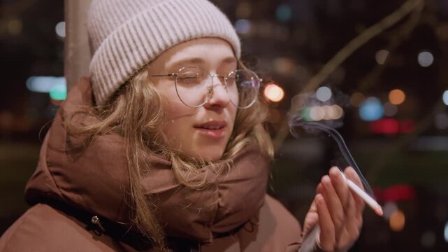 Nighttime city reflection. Silent walk amid glowing city lights. Woman pauses on quiet street under city illumination. Figures in winter clothing observe distant glowing skyline in silence