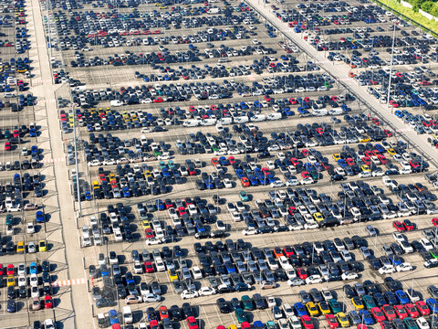 Aerial view of a massive car storage lot with thousands of vehicles parked in organized rows at a logistics hub in Rivalta di Torino, Piedmont, Italy.
