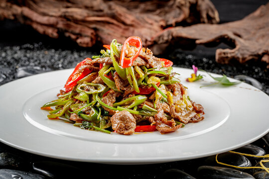 Stir-fried beef with yellow peppers served on a white round plate