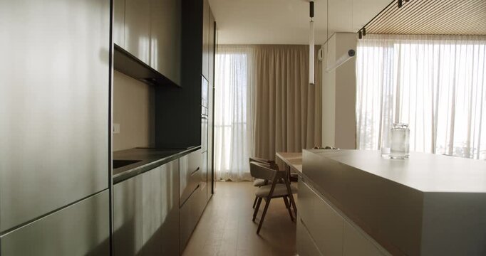 Modern kitchen interior with minimalist design, featuring an island and dining area. Stylish cabinets and contemporary lighting create a luxurious atmosphere.