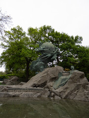 Fototapeta premium Weltpostdenkmal - allegorical bronze globe and reclining figure on rocky plinth in Bern park