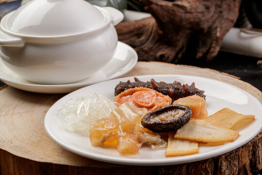 The white porcelain tableware on the pine cutting board clattered against the rich seafood soup.
