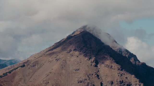 Majestic mountain peak in Morocco, North Africa. Clouds drift over the summit. Stunning natural beauty, ideal for travel, adventure, and nature documentaries. Explore the rugged landscapes