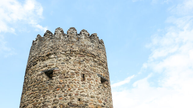Weathered stone tower with battlements topping an old fortress wall, showcasing historic architecture and the enduring legacy of ancient fortifications