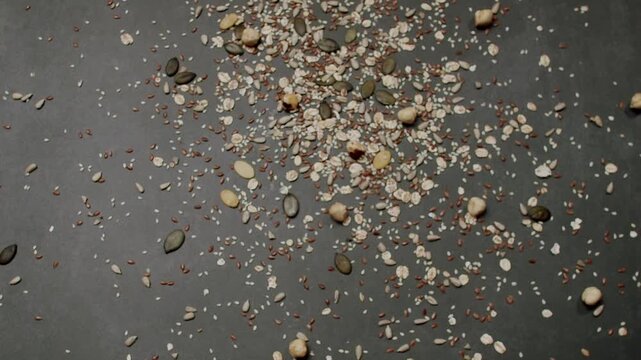 Close-up view of various nuts and seeds scattered on a dark textured surface. Perfect for concepts related to nutrition, health, and natural foods. Assorted Nuts And Seeds Scattered