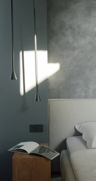 Sunlight streams into a modern bedroom, illuminating a minimalist bedside table with an open magazine. The room features a gray wall, soft lighting, comfortable bed, stylish atmosphere.