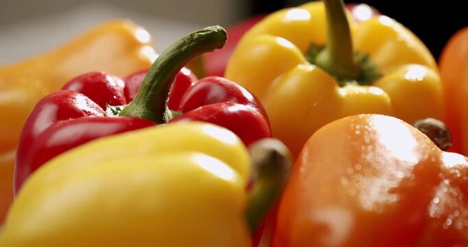 Vibrant close-up of red, yellow, and orange bell peppers, glistening with water droplets in sunlight. Capture the freshness and vivid colors of these vegetables, perfect for healthy eating concepts.