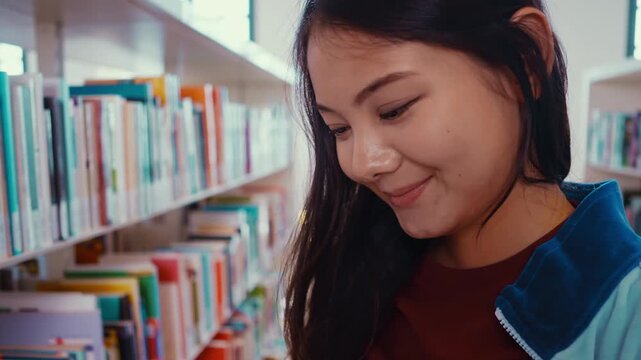 Female chinese student holding books studying in a library
