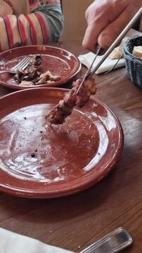Succulent pieces of roasted lamb being removed from a traditional  skewer. Authentic "Lechazo de Traspinedo" from Spain, (in the province of Valladolid, Castile Le&oacute;n), a gourmet culinary experience.