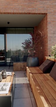 Modern balcony or terrace with wooden furniture, a potted plant, and comfortable seating, perfect for relaxation or outdoor dining.
