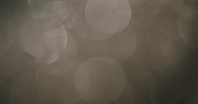 Elegant, abstract warm grey and beige bokeh lights creating a gentle, sparkling, and out-of-focus background effect, perfect for festive or sophisticated visual themes and overlays