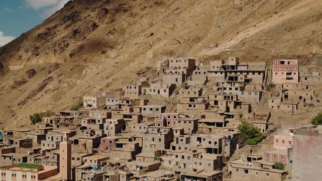Traditional Moroccan village nestled on a hillside. The houses are built from mud bricks and other simple, readily available materials. architecture evokes a sense of rustic charm.