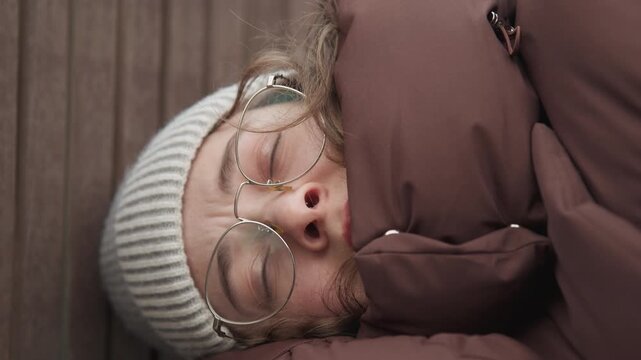 Peaceful woman wearing glasses in rest. Calm winter portrait of woman with glasses and knit hat sleeping peacefully. Closeup scene of woman peacefully sleeping in winter attire with gentle breathing