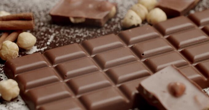 High-quality close-up image of appetizing milk chocolate bars with hazelnuts and cinnamon sticks on a textured background. Perfect for food and dessert concepts. Delicious Milk Chocolate Bar