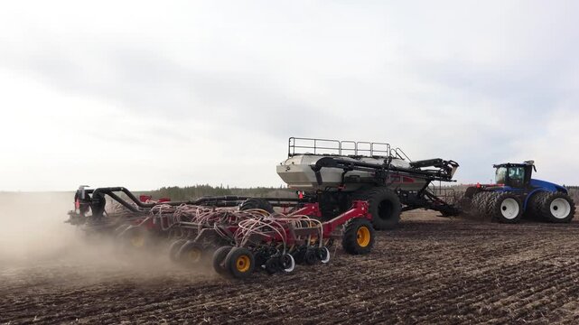 Large Tractor Pulling Seeder Through Cultivated Field, air seeder in action