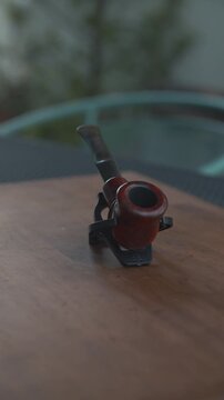 Primer plano detallado de pipa de madera cl&aacute;sica en soporte negro sobre mesa r&uacute;stica, formato vertical para redes sociales.