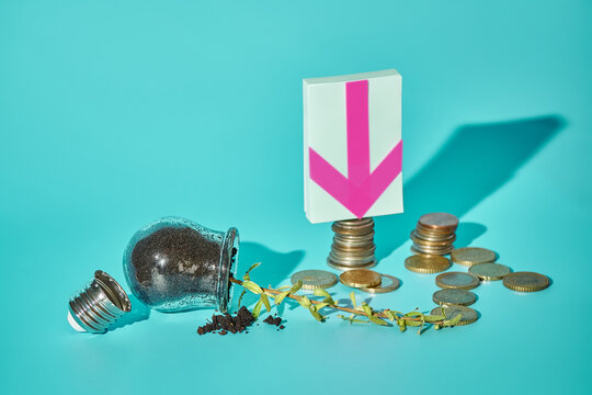 Fallen light bulb with sprout, euro coins and down arrow sticker on turquoise background, wasted innovation concept, copy space