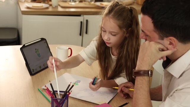 A daughter drawing with colored pencils at a table, guided by a father, with a tablet displaying a cactus image and art supplies nearby.
