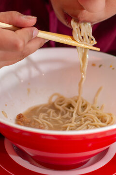 Close up of person eating ramen with chopsticks