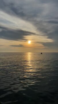 Golden Hour Ocean Timelapse Featuring Boat Silhouette and Moving Clouds