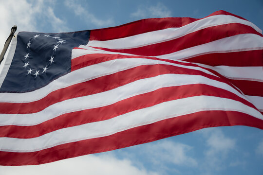 Besty Ross American Flag blowing in light breeze high angle against cloudy blue sky