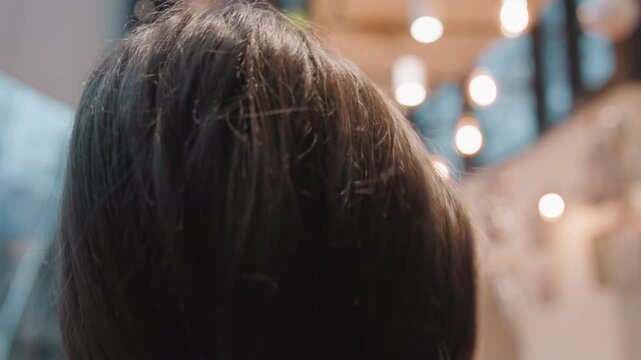 Young white woman adjusting glasses and bun in bistro with calm curiosity, delicate frames catch warm bokeh highlights, profile views show gentle expression, modern accessory detail, creative indoor