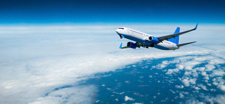 Commercial airplane flying over the clouds, air travel background with white airplane in the flight among high clouds in the atmosphere