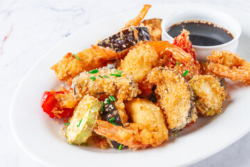 Fototapeta premium Shrimp and vegetable tempura, served with dipping sauce, on a white plate