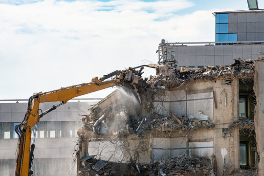 Construction site, demolition of reinforced concrete structure, gutting and renovation, hydraulic hammer dismantles building, caterpillar excavator machine