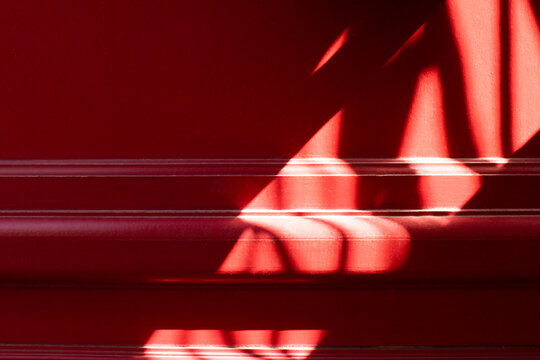 Red wall background with abstract sunlight shadow pattern