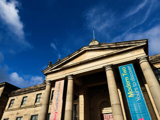 Obraz premium Neoclassical Modern Two Dean Gallery museum facade with grand columns and colorful event banners at Modern Two gallery in Edinburgh, Scotland, UK under a dramatic blue sky