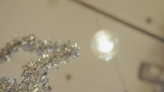 Closeup silver tinsel garland shimmering under warm ceiling lights, shallow depth of field captures sparkling metallic flakes and delicate loops, visual merchandiser installation vibe, elegant festive